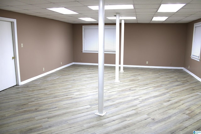 basement featuring light wood-type flooring and a paneled ceiling