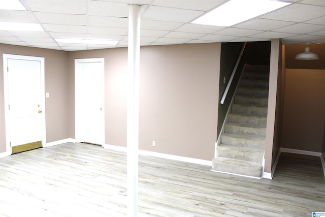 basement with a paneled ceiling and light wood-type flooring