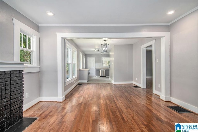 unfurnished living room featuring a chandelier, a fireplace, wood-type flooring, and ornamental molding