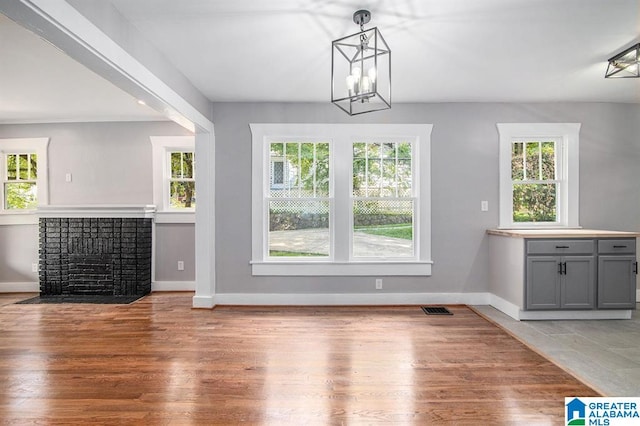 unfurnished dining area with hardwood / wood-style floors, a healthy amount of sunlight, and an inviting chandelier