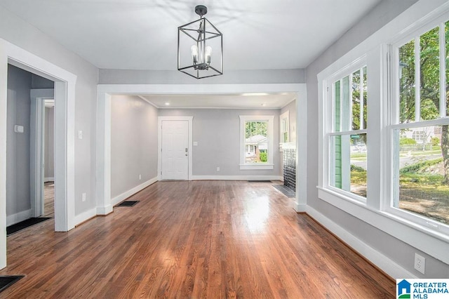 unfurnished dining area featuring dark hardwood / wood-style flooring and an inviting chandelier