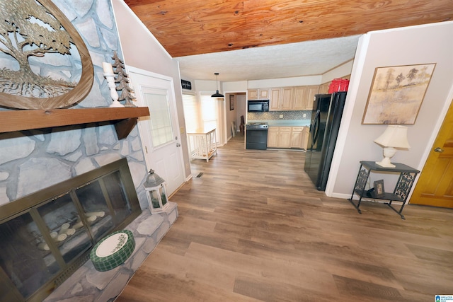 living room with hardwood / wood-style floors, a stone fireplace, and lofted ceiling