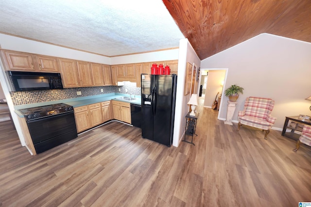 kitchen with sink, dark wood-type flooring, tasteful backsplash, vaulted ceiling, and black appliances