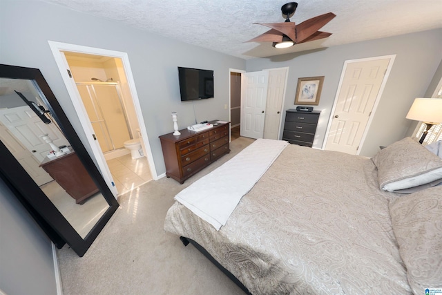 bedroom featuring ceiling fan, light colored carpet, a textured ceiling, and connected bathroom