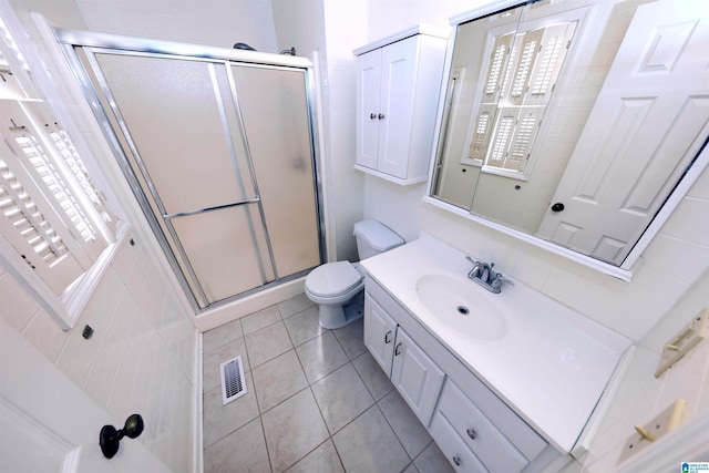 bathroom featuring toilet, vanity, tile patterned floors, and walk in shower