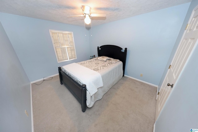 bedroom with a textured ceiling, light colored carpet, and ceiling fan