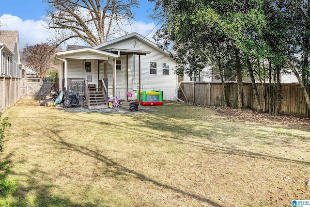 rear view of house with covered porch and a lawn