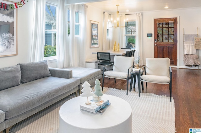 living room featuring wood-type flooring, an inviting chandelier, and crown molding