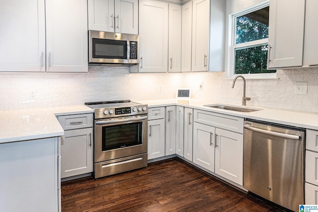 kitchen with appliances with stainless steel finishes, backsplash, dark hardwood / wood-style floors, and sink