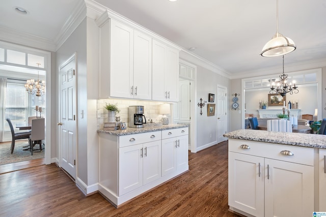 kitchen featuring light stone countertops, backsplash, dark wood-type flooring, pendant lighting, and white cabinets