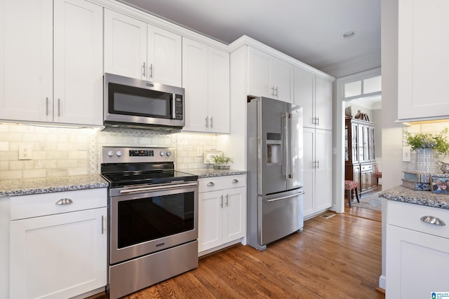 kitchen featuring stainless steel appliances, white cabinetry, tasteful backsplash, and dark wood-type flooring