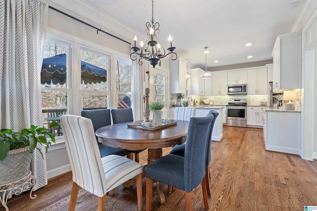 dining room with crown molding, light hardwood / wood-style flooring, a chandelier, and sink