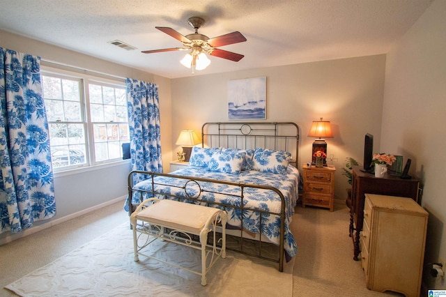 bedroom featuring ceiling fan, light carpet, and a textured ceiling