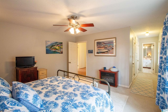 bedroom with a textured ceiling, ceiling fan, light carpet, and connected bathroom