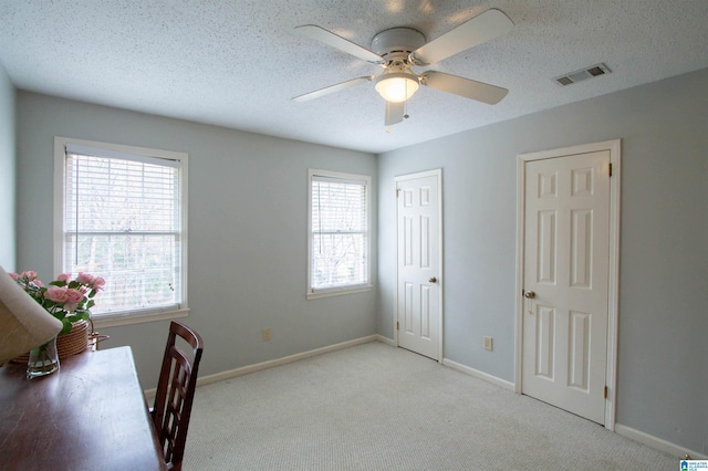 carpeted office with plenty of natural light, ceiling fan, and a textured ceiling