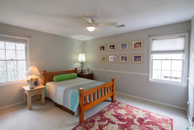 bedroom with carpet flooring, multiple windows, ceiling fan, and a textured ceiling