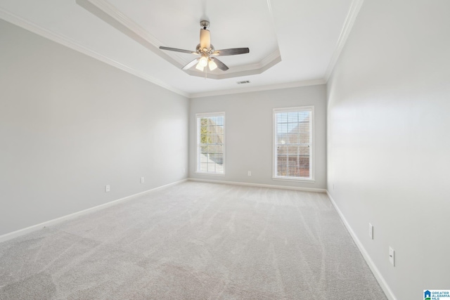 spare room with a tray ceiling, crown molding, ceiling fan, and light carpet