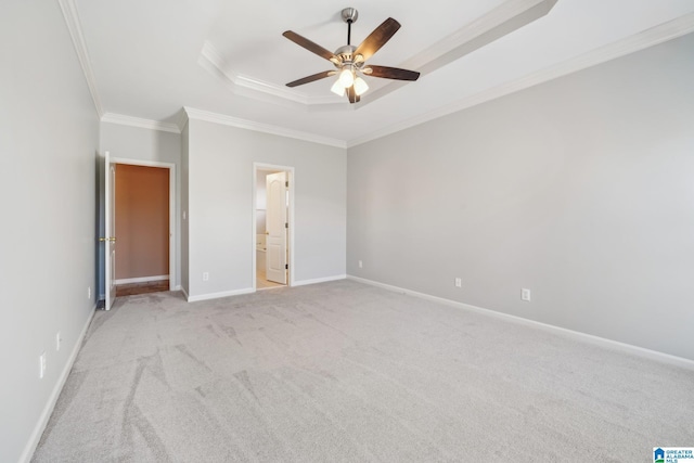 unfurnished bedroom featuring light carpet, a raised ceiling, crown molding, ceiling fan, and connected bathroom