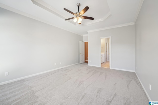 unfurnished bedroom featuring ensuite bathroom, light colored carpet, a raised ceiling, ceiling fan, and crown molding