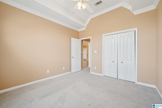 unfurnished bedroom featuring ceiling fan, a closet, light carpet, and ornamental molding