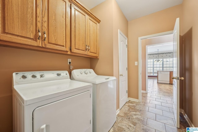 washroom with cabinets, washer and clothes dryer, and a notable chandelier