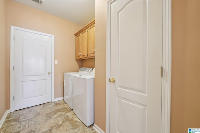 clothes washing area with cabinets and washing machine and dryer