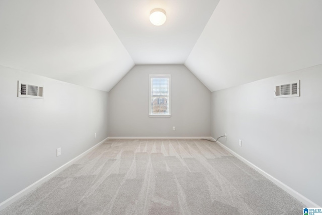 bonus room with light colored carpet and vaulted ceiling