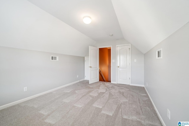 additional living space with light colored carpet and vaulted ceiling