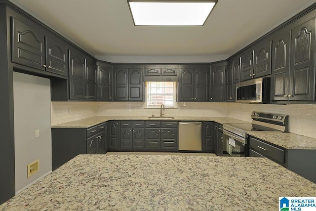 kitchen with appliances with stainless steel finishes, light stone countertops, and sink