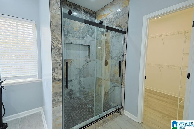 bathroom featuring wood-type flooring, plenty of natural light, and an enclosed shower