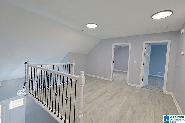 corridor with vaulted ceiling and light wood-type flooring