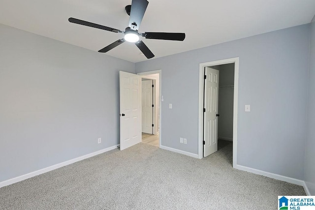 unfurnished bedroom featuring ceiling fan, a walk in closet, light colored carpet, and a closet