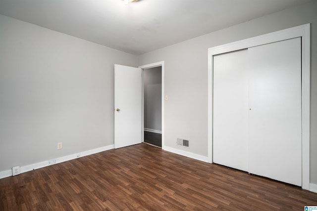 unfurnished bedroom featuring a closet, wood finished floors, visible vents, and baseboards