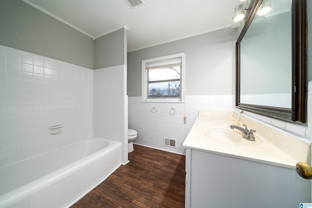 bathroom featuring toilet, wood finished floors, visible vents, tile walls, and ornamental molding