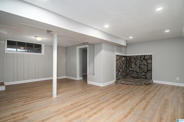 finished basement featuring a textured ceiling, baseboards, wood finished floors, and recessed lighting