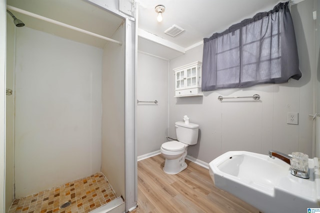 bathroom with a stall shower, visible vents, toilet, and wood finished floors