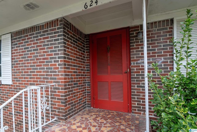 entrance to property featuring visible vents and brick siding