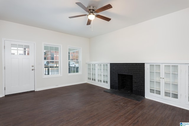 unfurnished living room featuring ceiling fan, dark hardwood / wood-style floors, and a brick fireplace