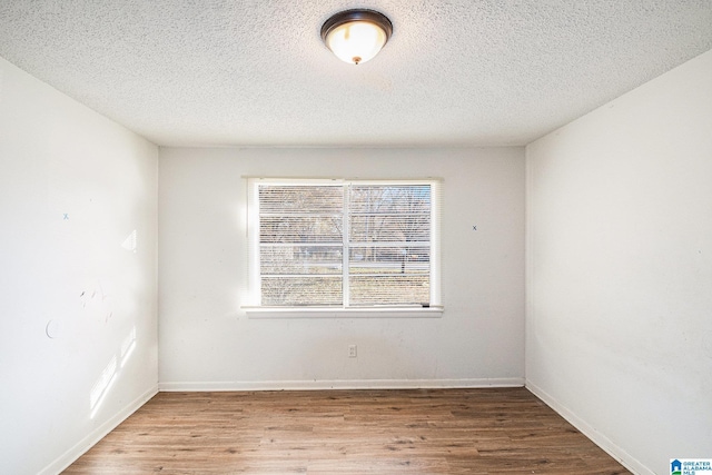 spare room featuring a textured ceiling and hardwood / wood-style flooring