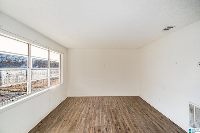 unfurnished room with dark hardwood / wood-style flooring and a textured ceiling