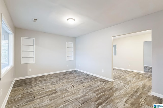 unfurnished room featuring built in shelves and wood-type flooring