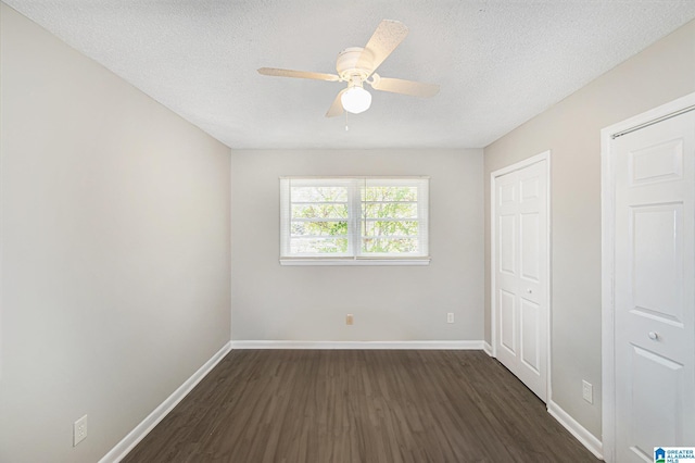 unfurnished bedroom with multiple closets, a textured ceiling, ceiling fan, and dark wood-type flooring