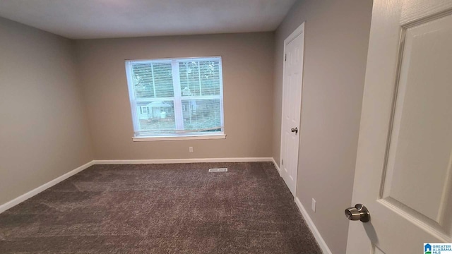 spare room with dark colored carpet