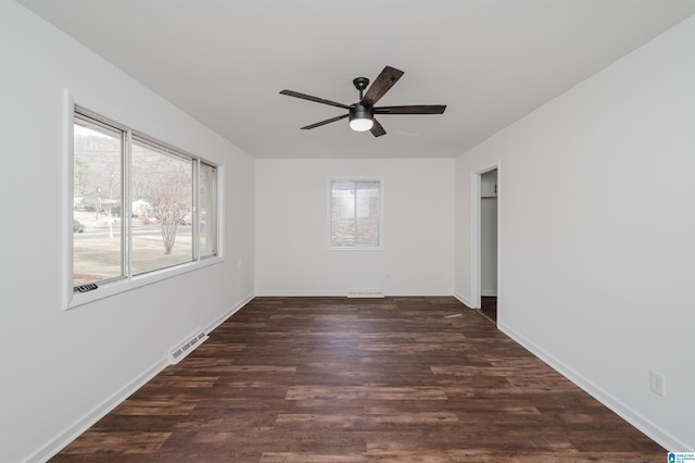 spare room with ceiling fan, dark wood-type flooring, and a wealth of natural light