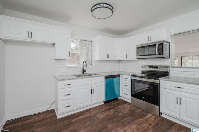 kitchen featuring appliances with stainless steel finishes, light stone counters, dark wood-type flooring, sink, and white cabinets