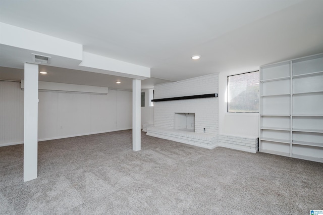 basement with light carpet and a brick fireplace