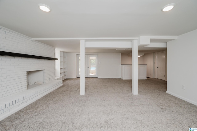 basement featuring a fireplace, light colored carpet, and brick wall