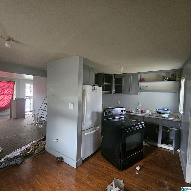 kitchen featuring dark hardwood / wood-style floors, black electric range oven, and stainless steel refrigerator