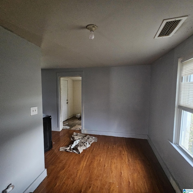 unfurnished room featuring wood-type flooring, vaulted ceiling, and a wealth of natural light