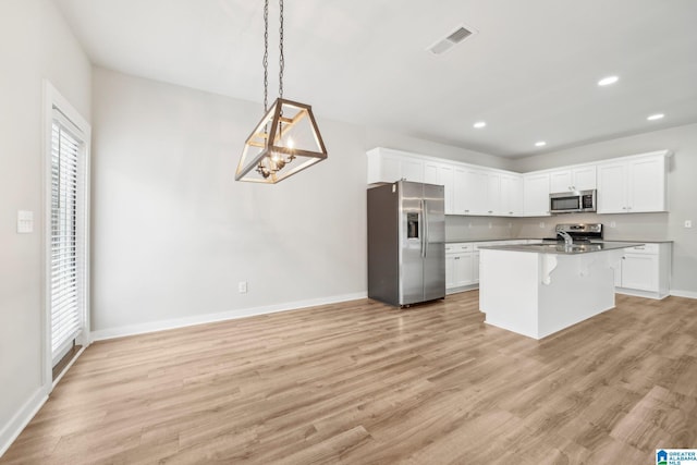 kitchen featuring white cabinets, light hardwood / wood-style flooring, stainless steel appliances, and an island with sink